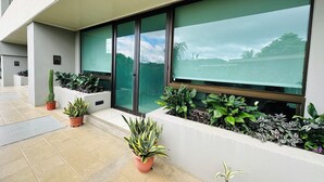 A modern building with large windows, potted plants, and a tiled floor. - Serene Beachside 2 bedroom and 2.5 bathroom condo. (Playa Hermosa)