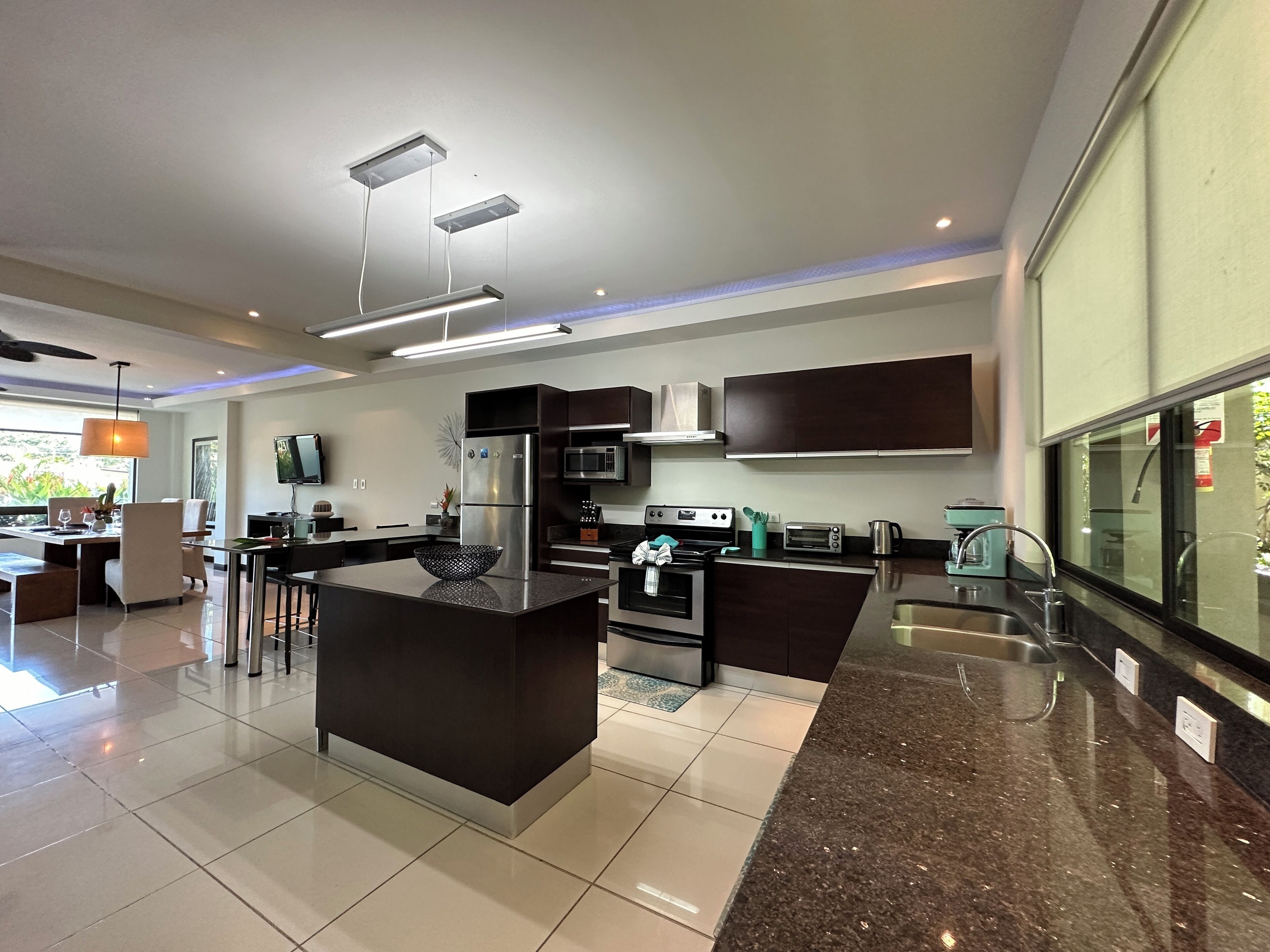 A modern kitchen with a central island, stainless steel appliances, and a large window.