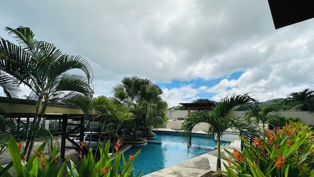 A pool area with palm trees and tropical plants. - Serene Beachside 2 bedroom and 2.5 bathroom condo. (Playa Hermosa)