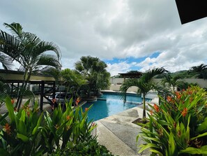 Un área de piscina con palmeras y plantas tropicales.