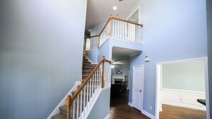 Un escalier avec des rampes en bois et des marches recouvertes de moquette, menant à un deuxième étage.