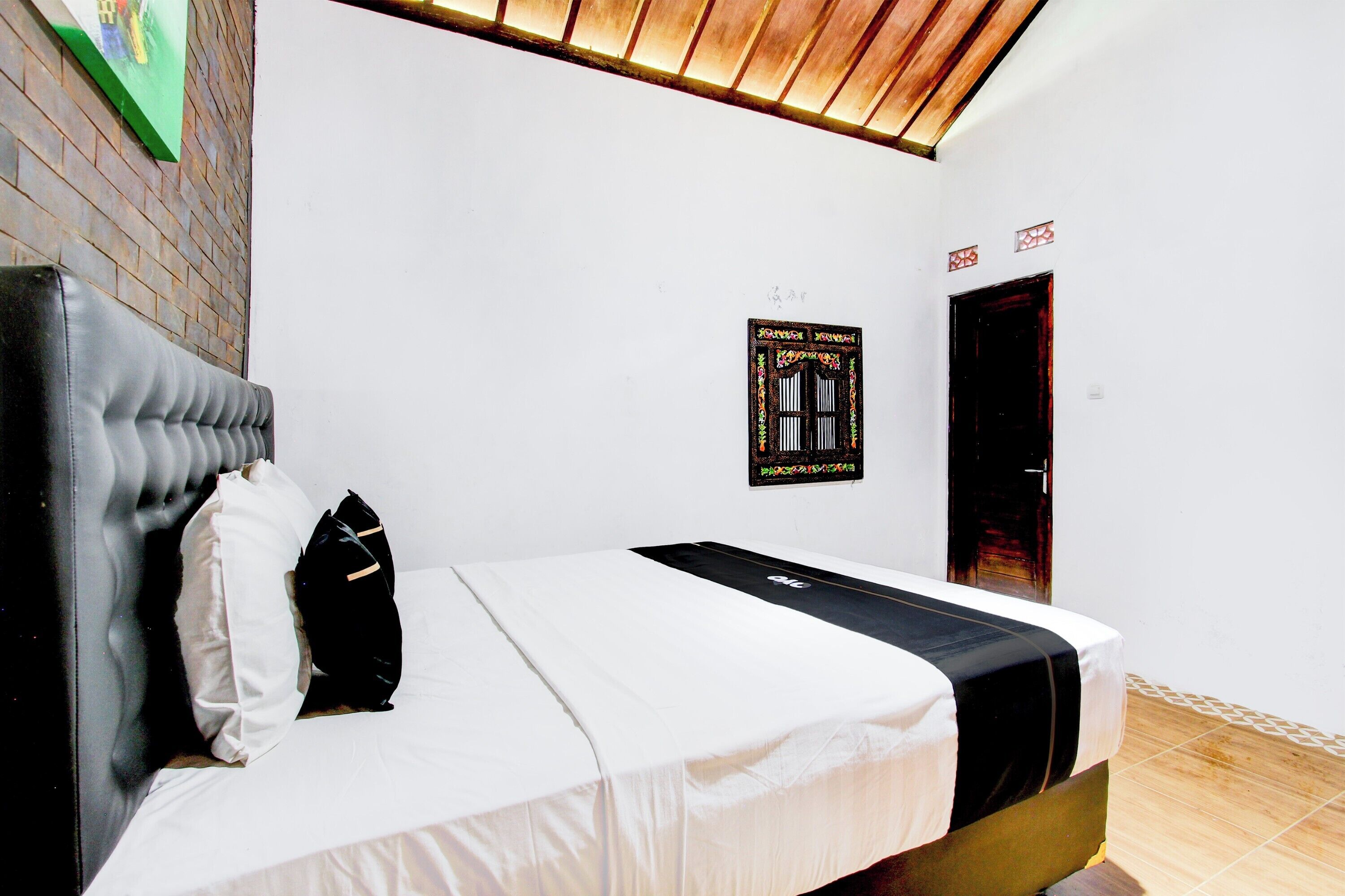 Een slaapkamer met een bed, hoofdeinde, kussen, deken, een aan de muur hangend poster en een deur.