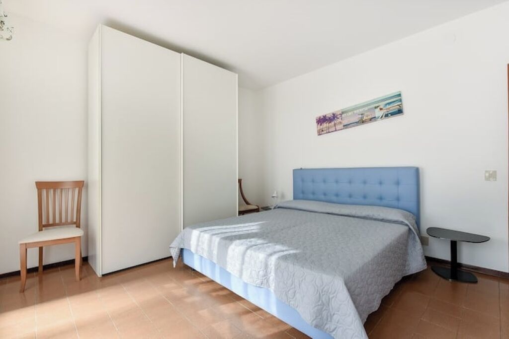 Une chambre à coucher avec un lit, une chaise, une petite table et un tableau accroché au mur.