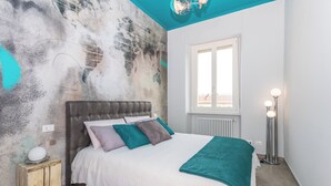 A bedroom with a bed, a window, a radiator, and a floor lamp. - Casa Ester in San Salvario by Wonderful Italy (Turin)