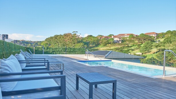 Une terrasse en bois avec des chaises longues et une piscine.