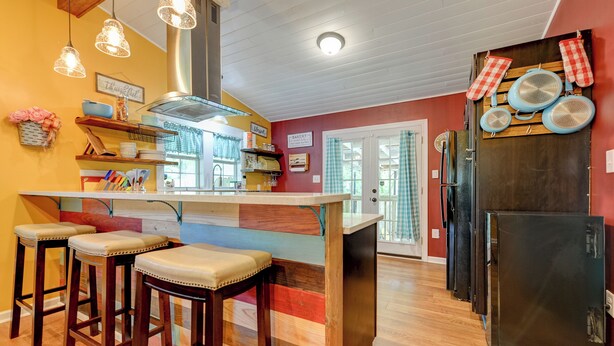 A kitchen with a wooden island, bar stools, hanging lights, and a refrigerator. - The Farm Haus (Meridian)