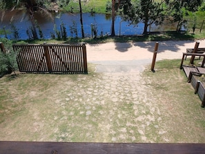 A grassy area with a wooden fence, a paved path, and a body of water.