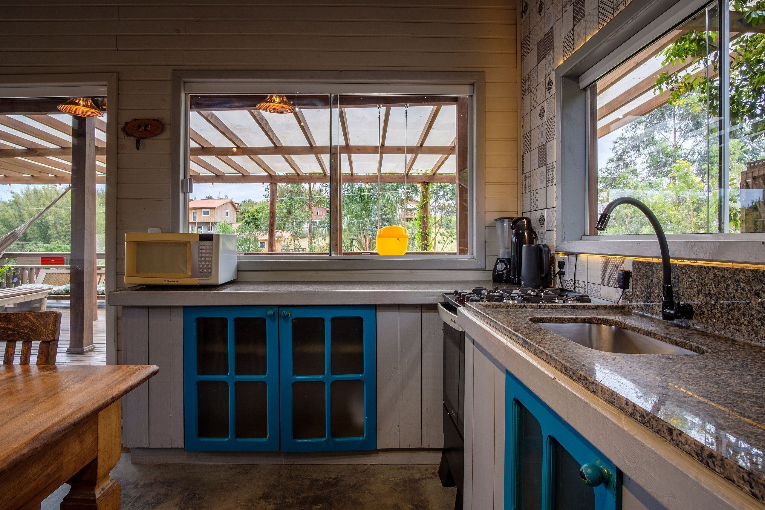 Una cocina con ventana, microondas, lavabo y estufa.