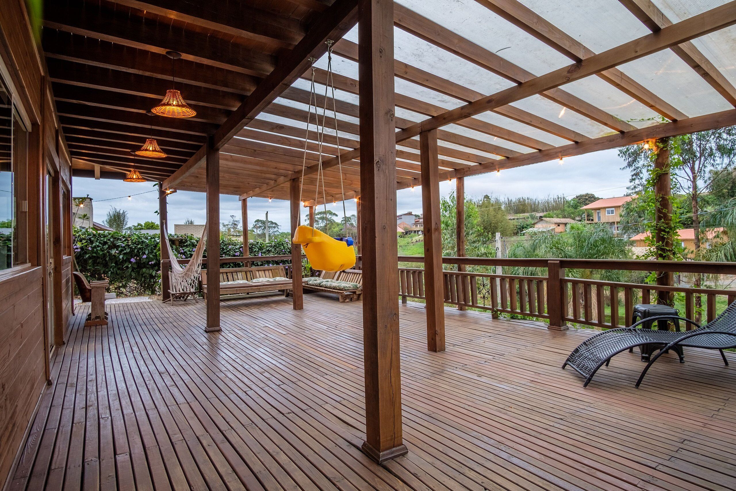 A wooden deck with a pergola, outdoor seating, and a hammock.