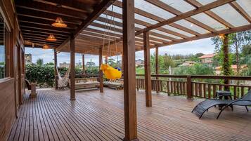 A wooden deck with a pergola, outdoor seating, and a hammock.
