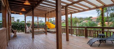 A wooden deck with a pergola, outdoor seating, and a hammock.