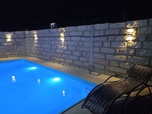 An outdoor swimming pool with a brick wall and built-in lighting. - Franca's House - Piscina - Praia do Rosa (Imbituba)