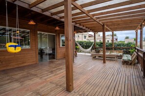 A wooden deck with a hammock and outdoor seating.