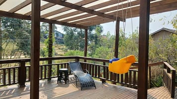 Relax on the shaded deck with a lounge chair and small table amidst lush greenery.