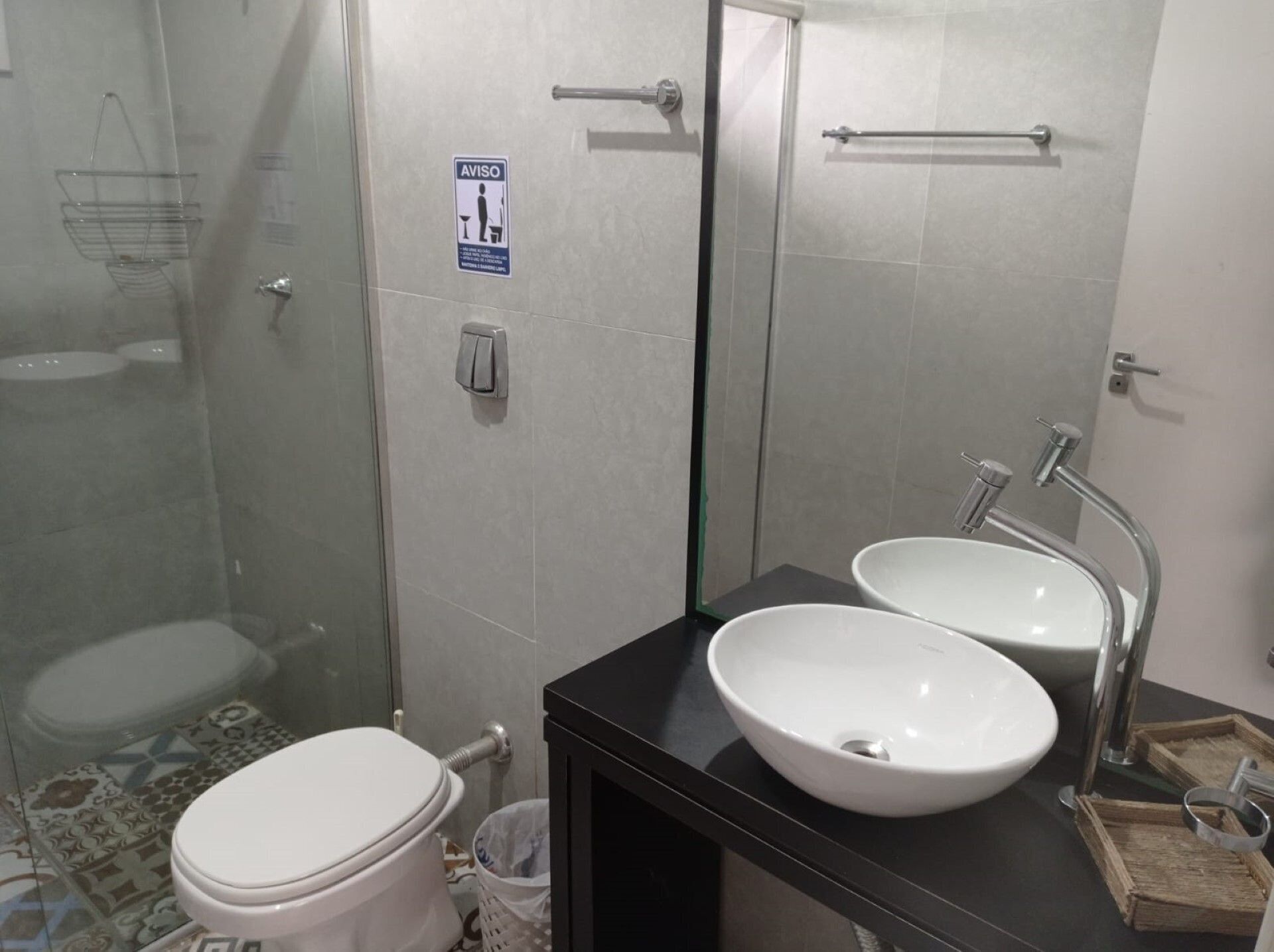 A bathroom with a toilet, a sink, a glass shower enclosure, and a mirror.