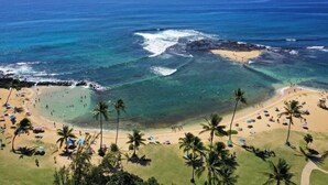 A beach with clear turquoise waters, palm trees, and people enjoying the beach.