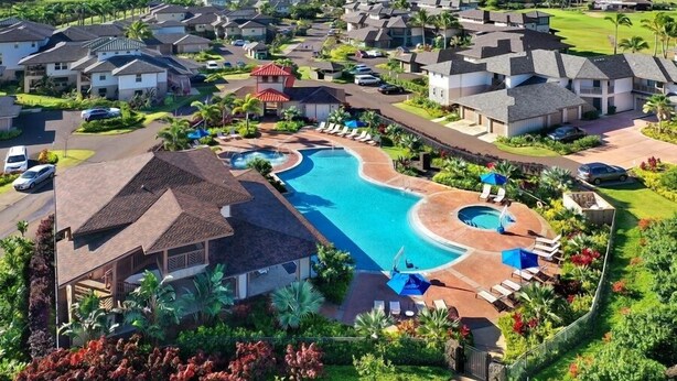 A resort with multiple houses, a swimming pool, and a view of the ocean.