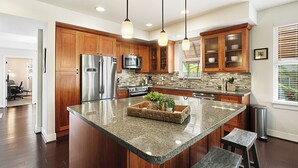 A modern kitchen with wooden cabinets, stainless steel appliances, and a granite island.