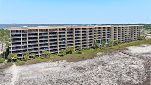 A multi-story hotel with a flat roof, numerous balconies, and a view of the ocean.
