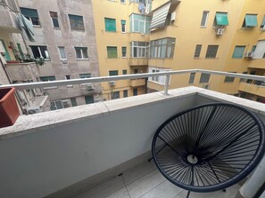 A balcony with a metal railing, a potted plant, and a view of adjacent buildings.