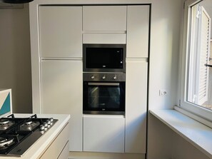 Una cocina compacta con horno integrado y cocina a gas.
