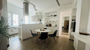 A modern kitchen with white cabinets, a round dining table with four chairs, and a large window providing natural light. - Agliardi House at the Vatican (ROMA)
