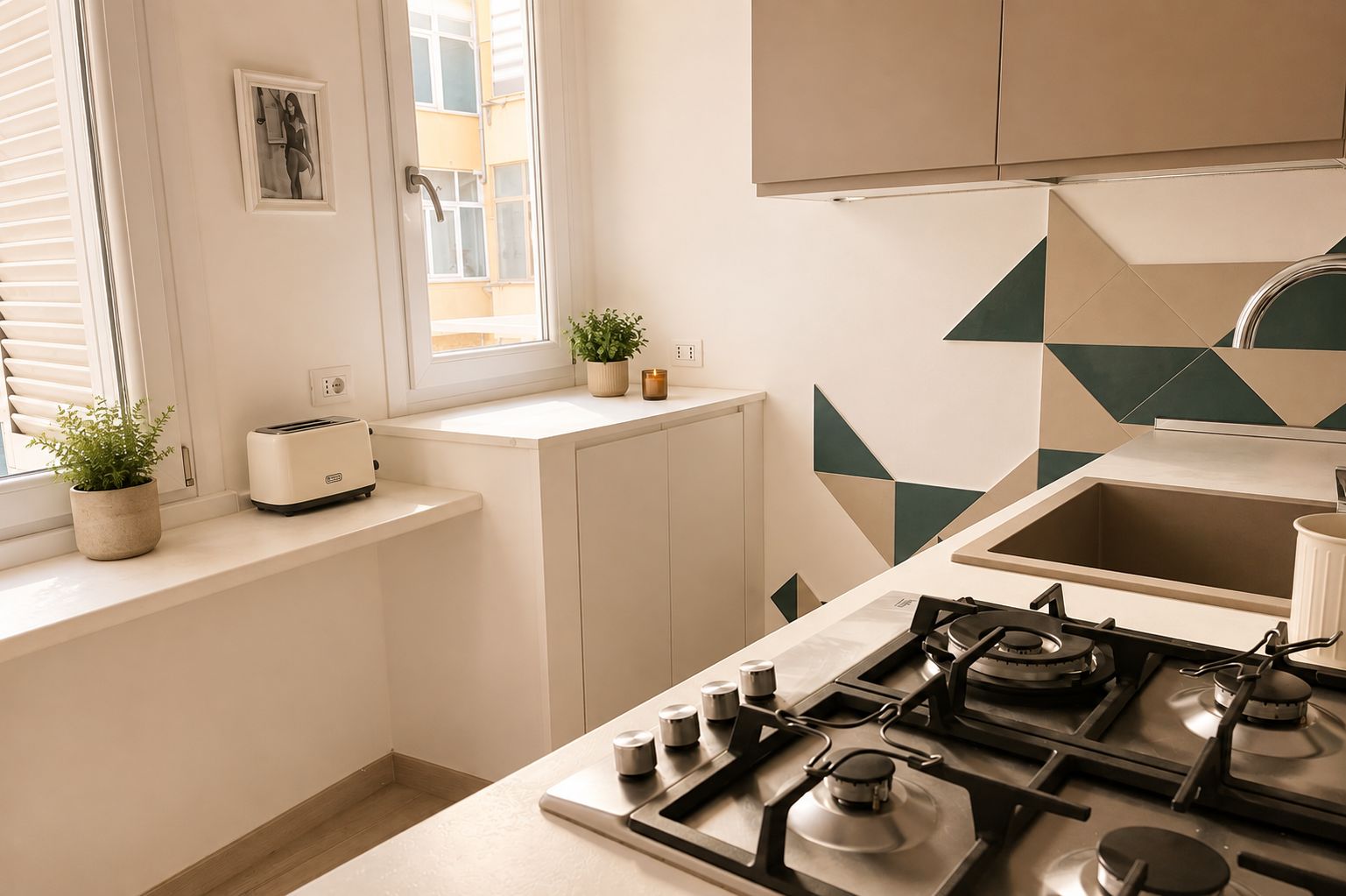 A modern kitchen with a gas stove, a toaster, and a window with blinds.