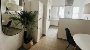 A modern kitchen with white cabinets, a large mirror, and a potted plant. - Agliardi House at the Vatican (ROMA)