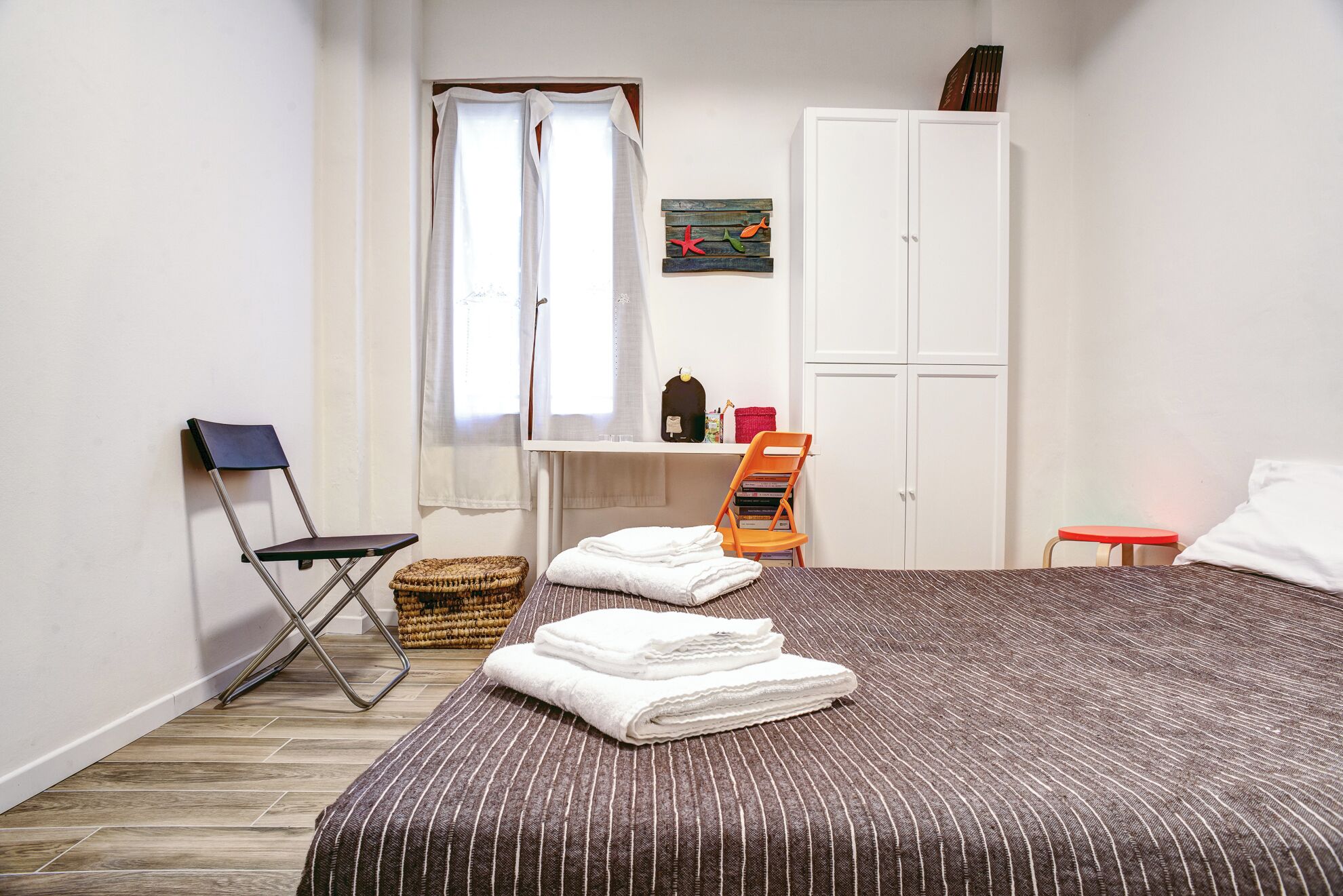 Une chambre à coucher comprenant un lit, un bureau, une chaise et une armoire.