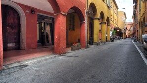 Una calle estrecha flanqueada por edificios con puertas de arco y fachadas en tonos rojo y amarillo.