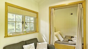 Um quarto aconchegante com um sofá verde, uma janela com cortinas e uma cama com toalhas.