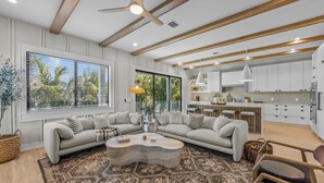 A modern living room with a sectional sofa, a coffee table, and a large window with blinds. - Welcome to Set in Sand! (Bradenton Beach)