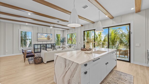 A modern kitchen with a marble island, wooden beams, and large windows. - Welcome to Set in Sand! (Bradenton Beach)