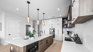 Eine moderne Küche mit weißer Arbeitsplatte, Holzschränken und Pendelleuchten.