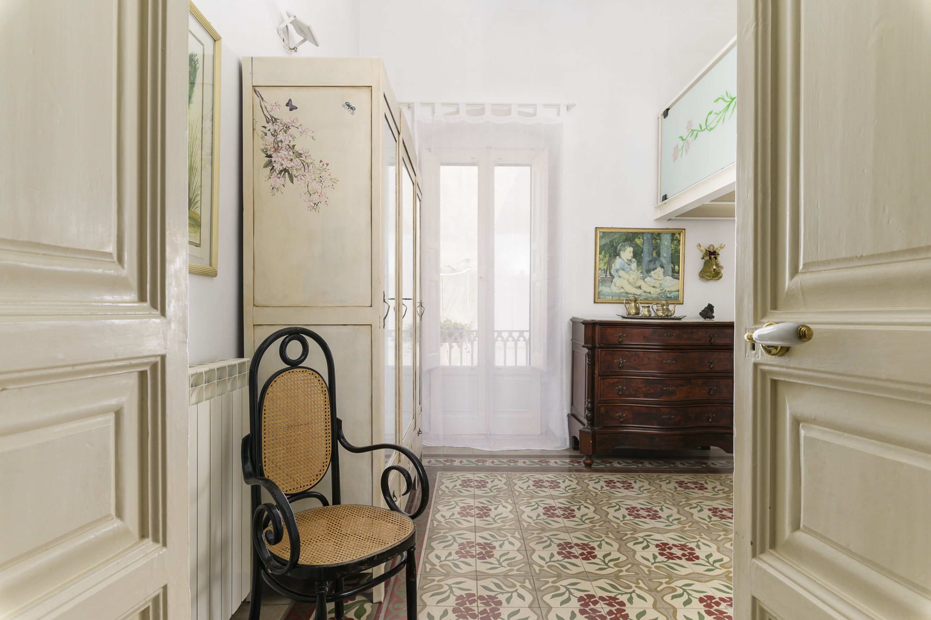 Un couloir avec une chaise, une commode et une porte.