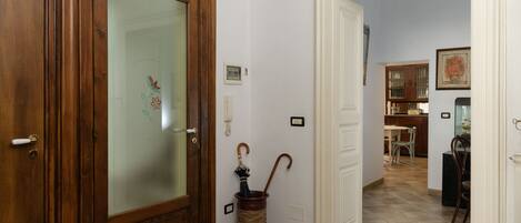 A hallway with a wooden door, a glass door, and a trash can with an umbrella.