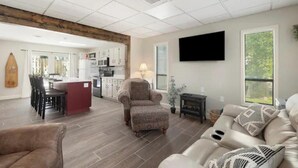 A spacious living area with a kitchen, dining area, and a large window providing natural light. - Branson Downtown Trolley House (Branson)