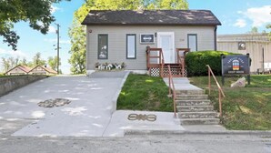 A small building with a front door, a staircase, and a sign that reads "Trolley Stop Guest House." - Branson Downtown Trolley House (Branson)