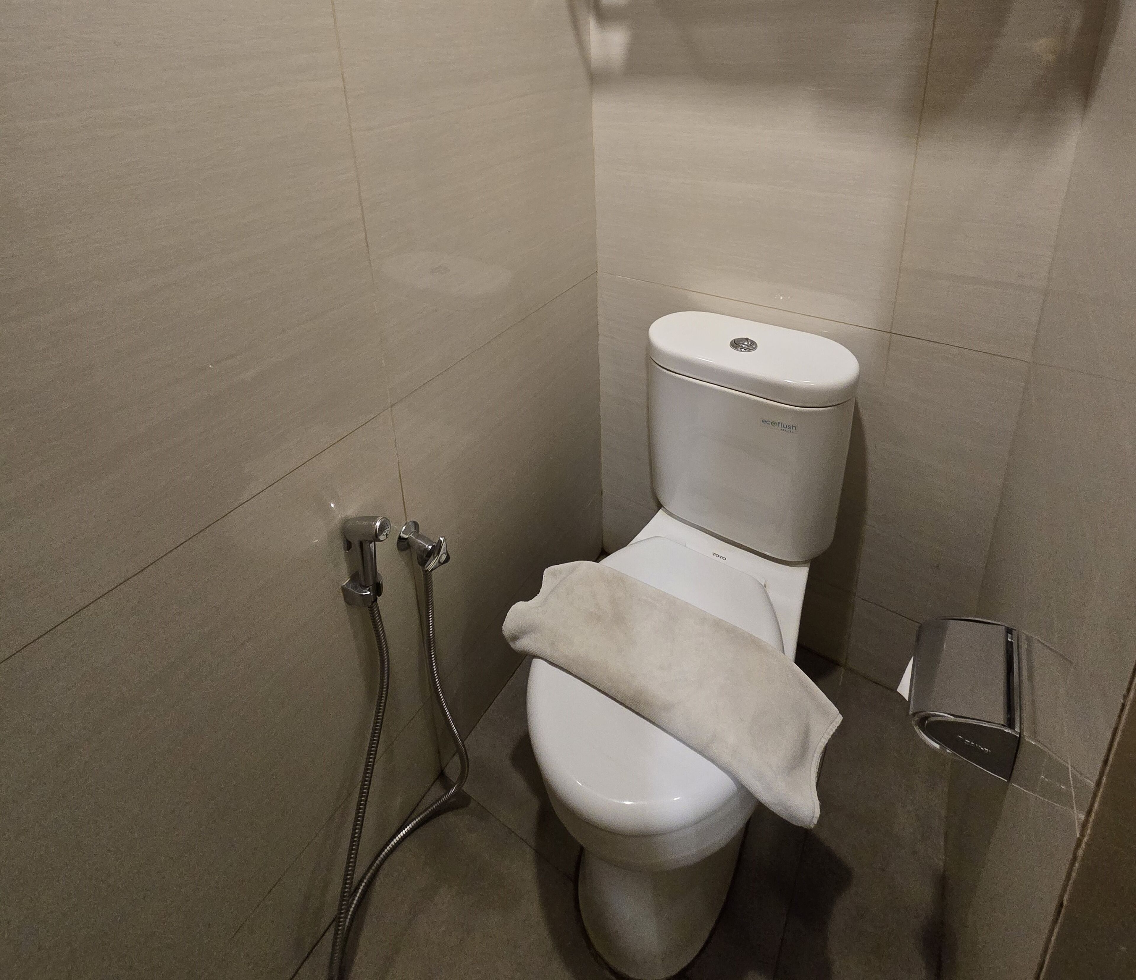 A bathroom with a toilet, a shower, and a towel rack.