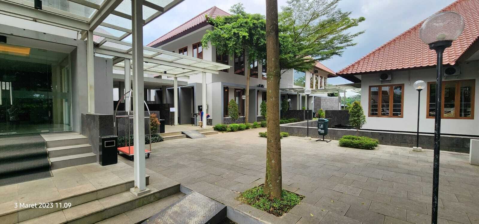 Un edificio moderno con entrada cubierta, zona de estacionamiento y un jardín bien cuidado.
