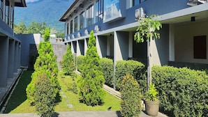 A modern building with multiple balconies, surrounded by well-maintained greenery and a clear view of a mountain in the background. - PEPABRI Hotel & Resort (Cilimus)