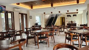 A spacious dining area with multiple wooden tables and chairs, a staircase, and a modern kitchen visible in the background. - PEPABRI Hotel & Resort (Cilimus)
