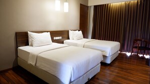 A hotel room with two beds, wooden flooring, a wooden headboard, and a chair. - PEPABRI Hotel & Resort (Cilimus)
