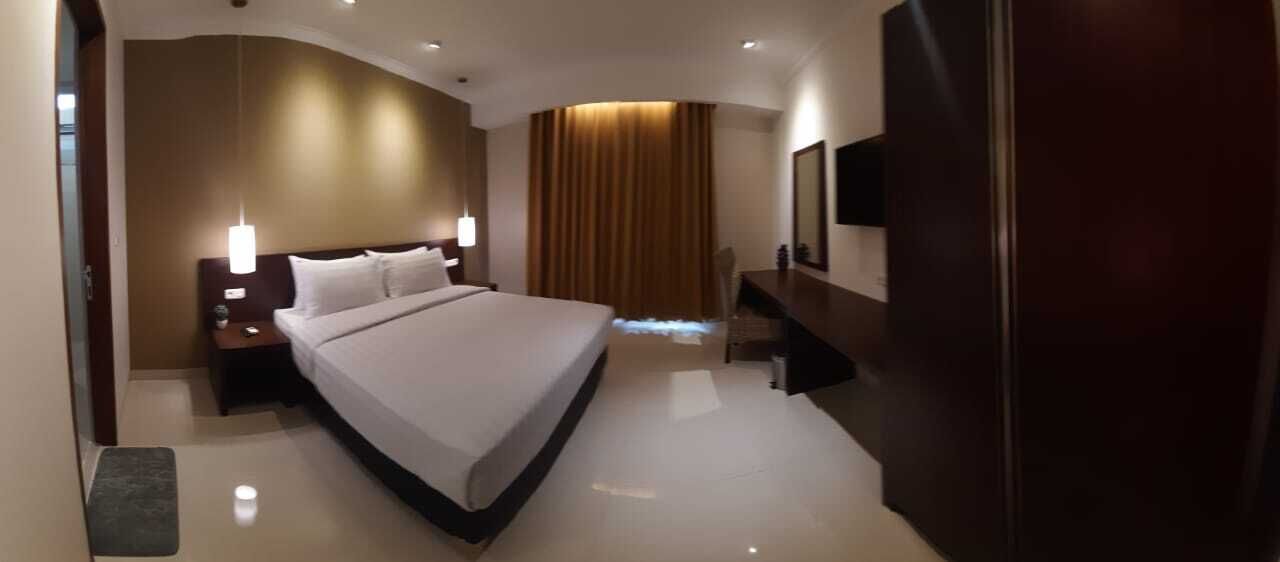 Une chambre d’hôtel moderne avec un grand lit, des tables de chevet, un bureau et une télévision.