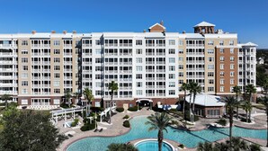 A large hotel with multiple floors, a swimming pool, and a landscaped area with palm trees. - FREE Daily Golf! Reflections 506 Amazing Views, Heated Resort Pool & Hot Tub! (Panama City)