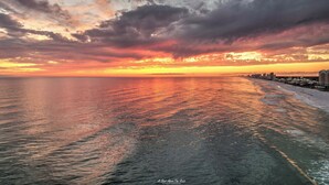 A coastal cityscape at sunset with a view of the ocean and buildings along the shore. - FREE Daily Golf! Reflections 506 Amazing Views, Heated Resort Pool & Hot Tub! (Panama City)