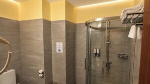 Un baño moderno con ducha de vidrio, inodoro y lavamanos con una toalla.