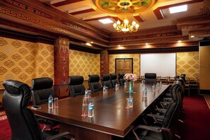 A conference room with a long table, multiple chairs, and a projector screen.