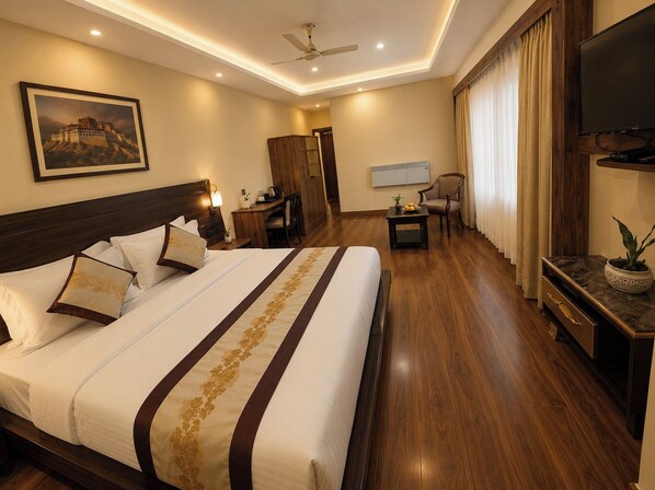 A hotel room with a large bed, a desk, a chair, a television, and a painting on the wall.