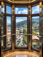 Una stanza d'angolo con ampie finestre che si affacciano su una città e montagne.